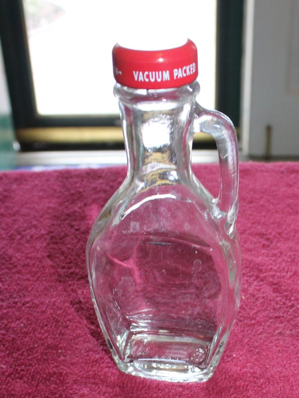 Vintage clear glass syrup or cruet bottle, side handle, a red screw-on top